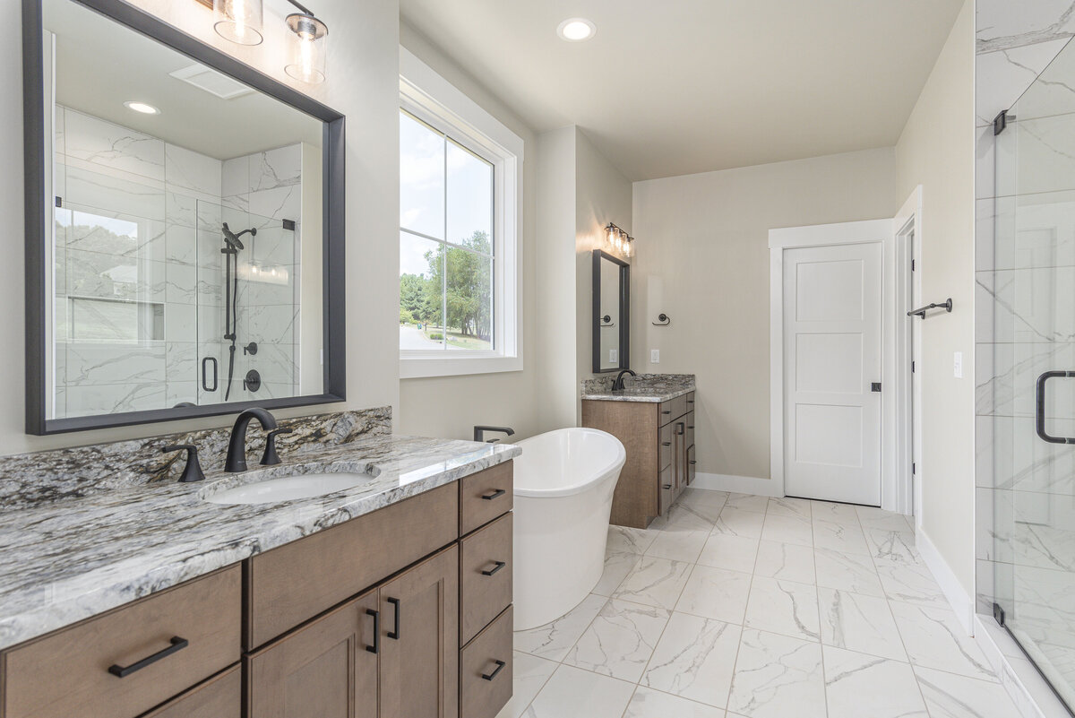 A large bathroom with marble counter tops and a walk in shower