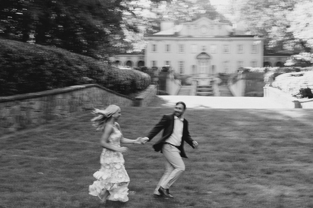 Couple runs across the front lawn of the Swan House at Atlanta History Center during engagement photos