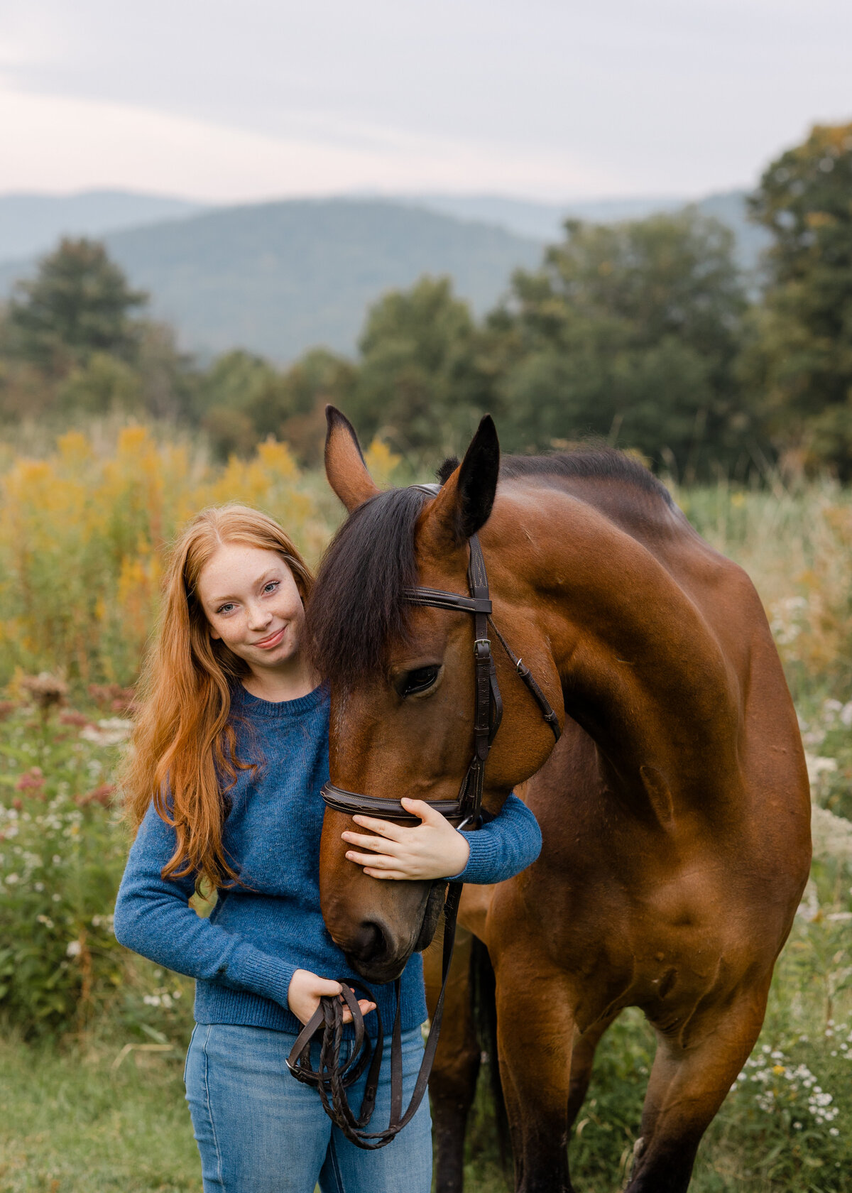 A Vermont high school senior stands with her horse in a vibrant field of wildflowers, celebrating her senior year with a heartfelt equestrian portrait session