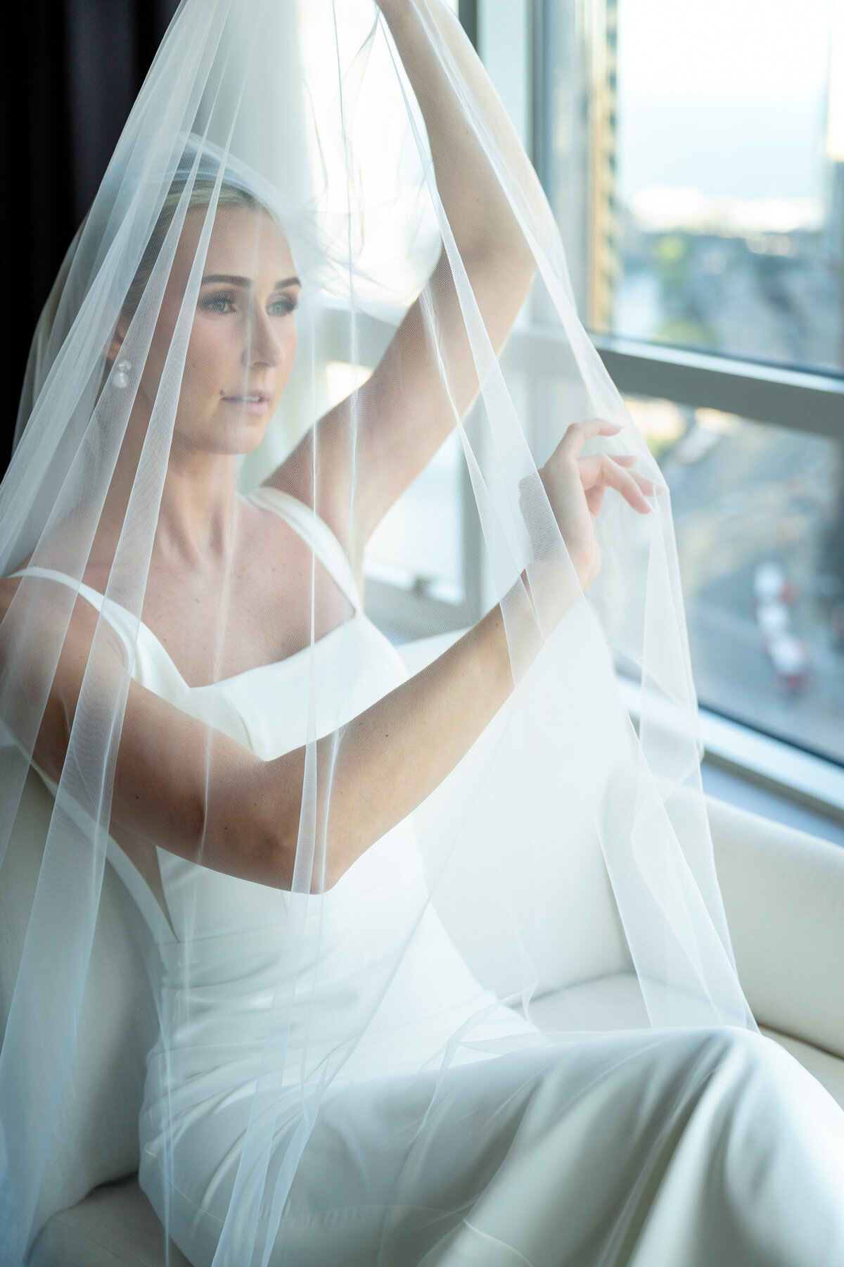 Getting ready picture of bride under the cathedral veil sitting on the lounge chair at Trump hotel suit