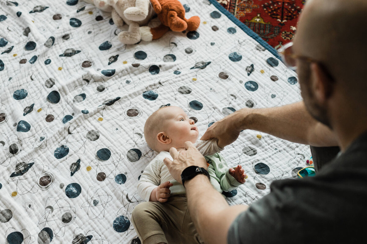 Father playing with baby on living room floor.