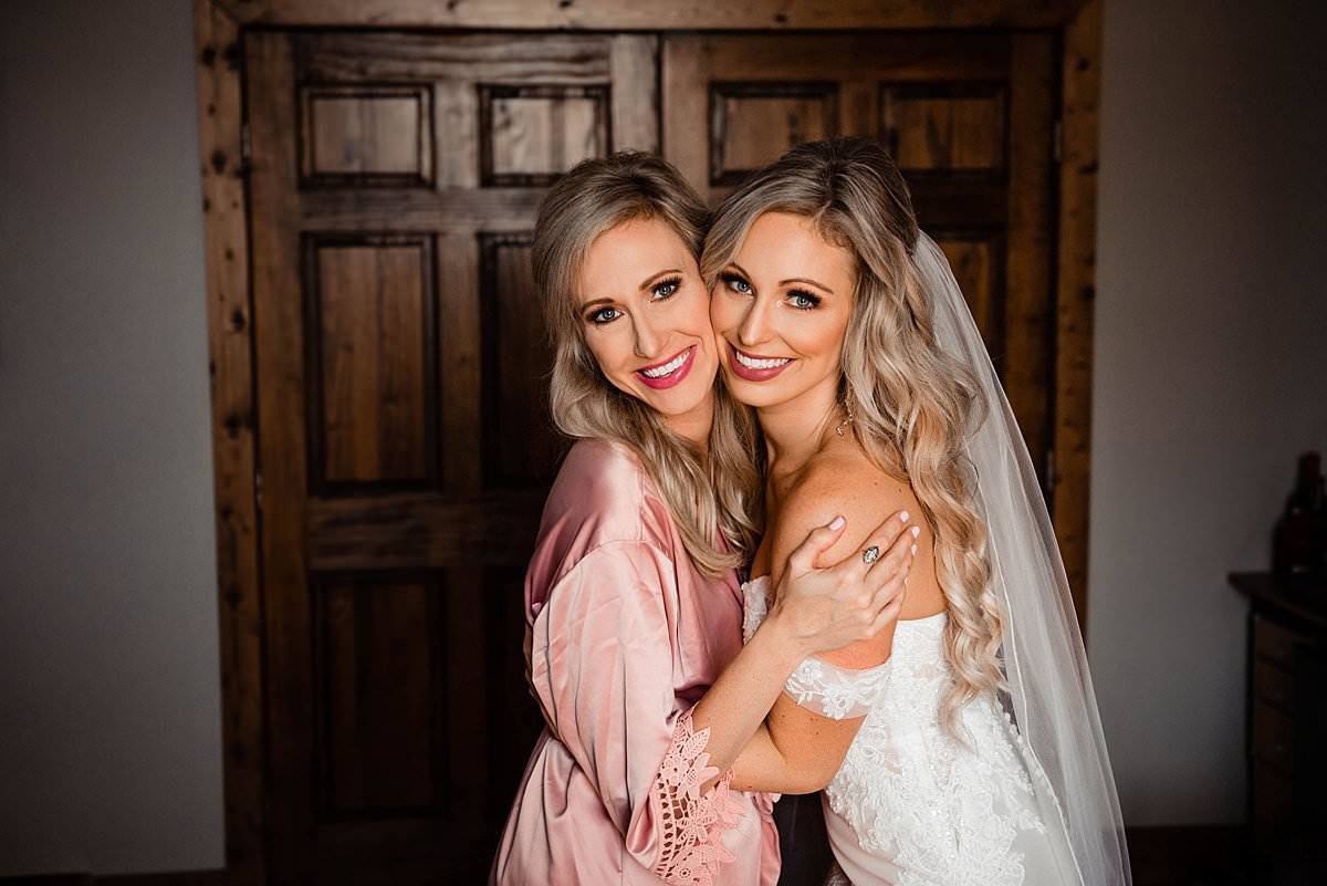 Bride hugging her sister and smiling at the camera