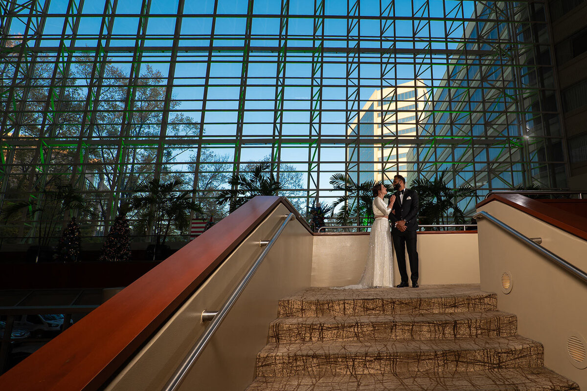 A wedding couple standing at the top of a staircase 