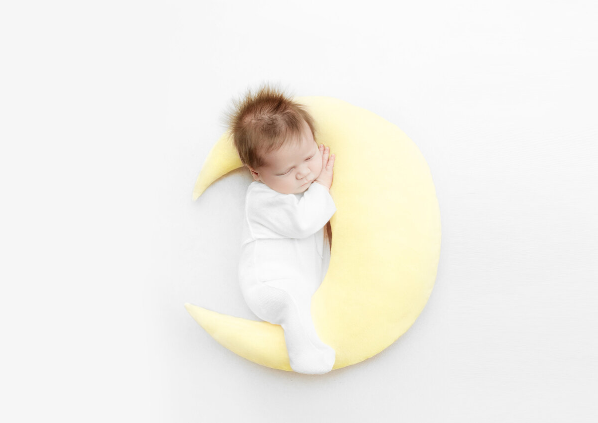 Newborn baby sleeping on a moon poser during newborn photoshoot in Franklin Tennessee photography studio