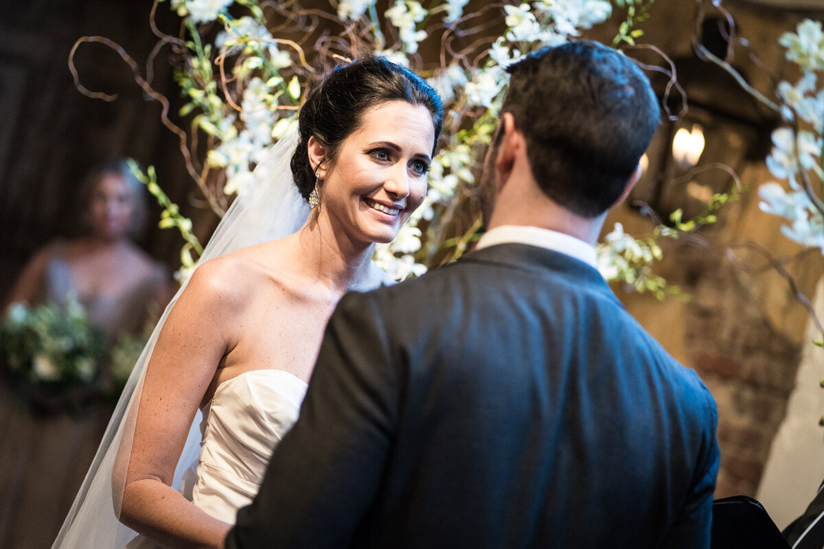 Bride smiles at groom during wedding ceremony