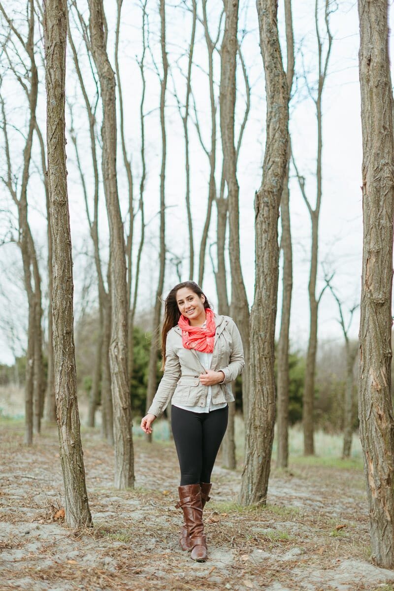 High school senior standing in a line of trees at Golden Garden Park in Seattle.