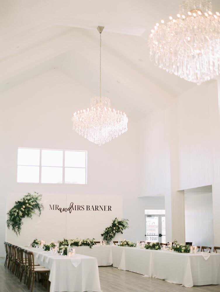 All white wedding reception room with a white backdrop design decorated with greenery