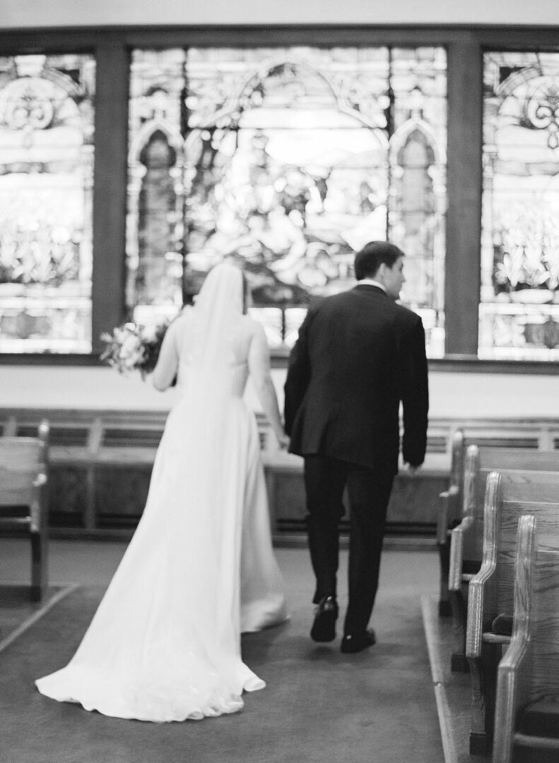Black and White of Bride and Groom Walking Down Aisle Photo
