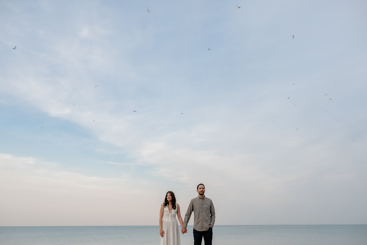 A couple holds hands in front of Lake Michiagn.