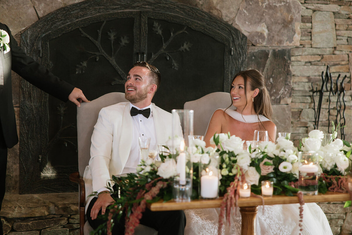  Bride and groom laughing during wedding reception toasts at Trillium Links & Golf Club in Cashiers, North Carolina.