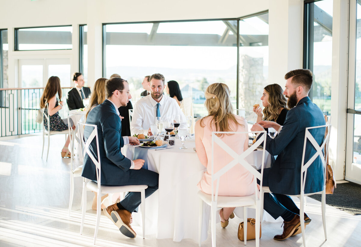Guests sitting at a wedding reception table before the meal is served at The Oaks captured by Denver wedding photographer