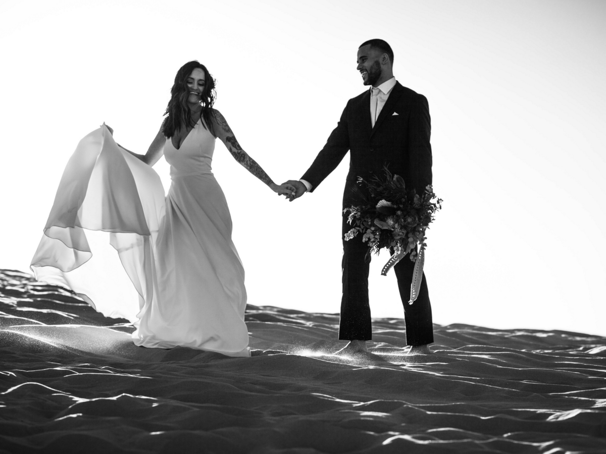 bride and groom walking across sand