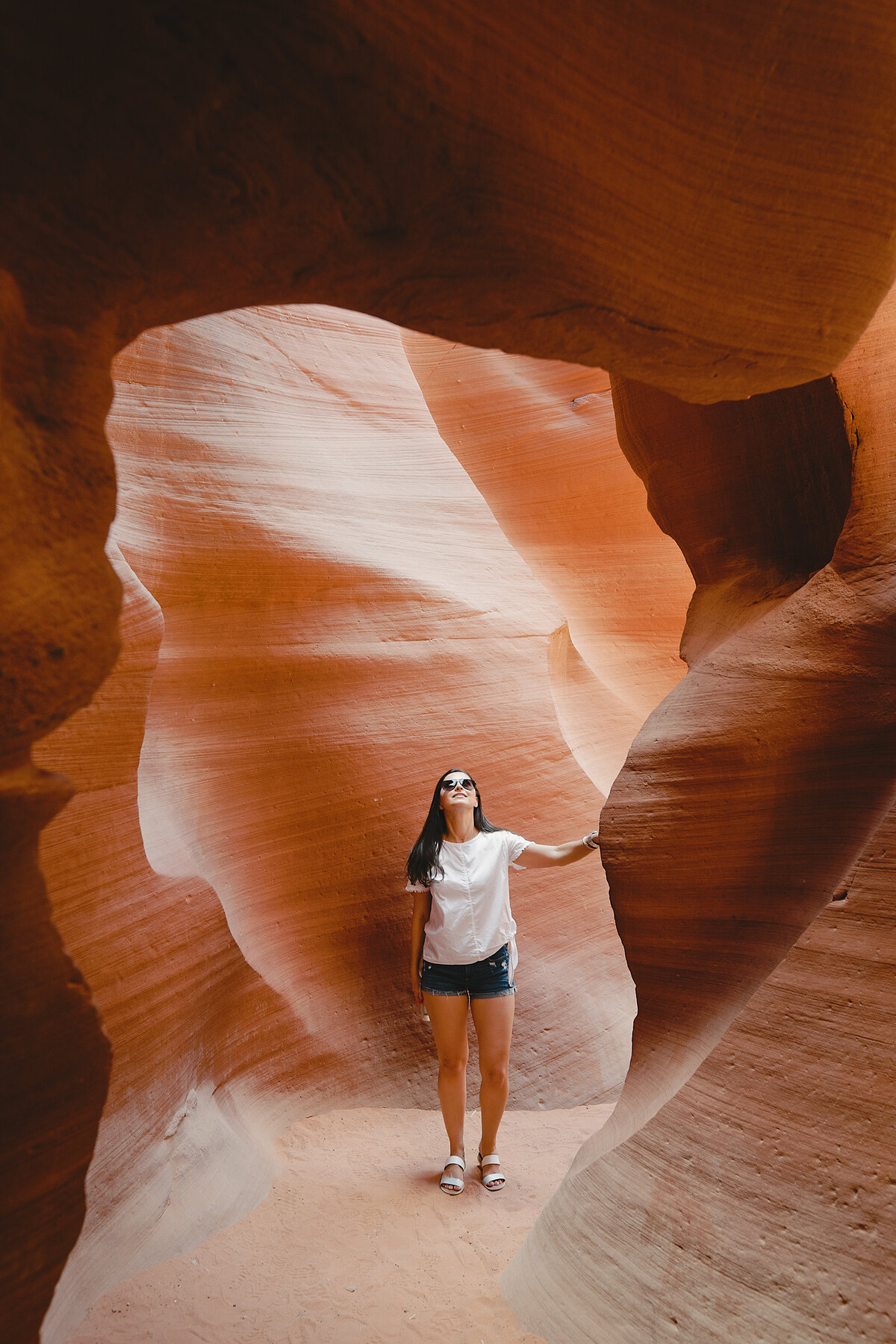 A woman exploring a stunning red rock slot canyon, surrounded by smooth, winding sandstone formations, part of a luxury Southwest adventure experience