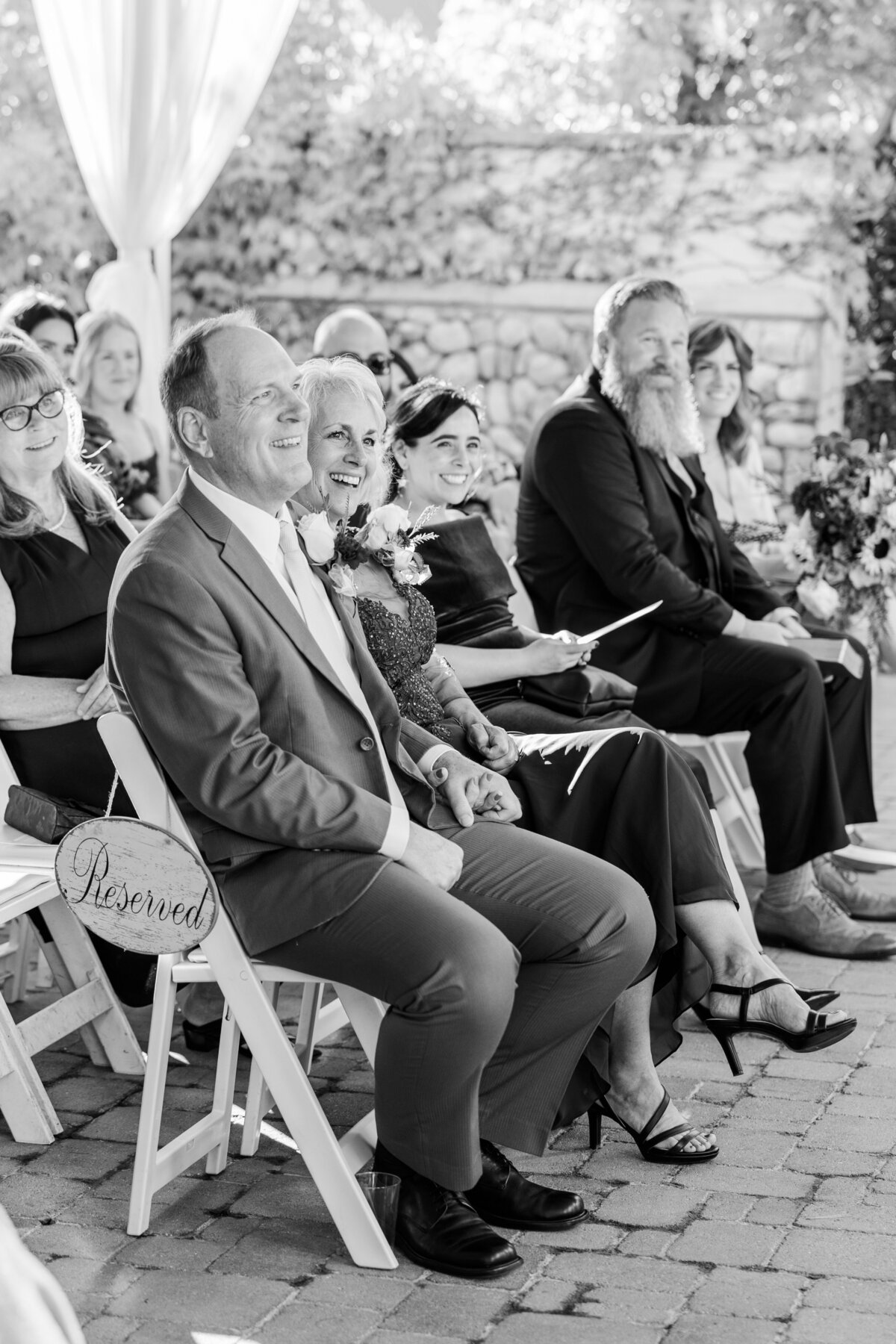 Parents of the bride smile during a wedding ceremony 