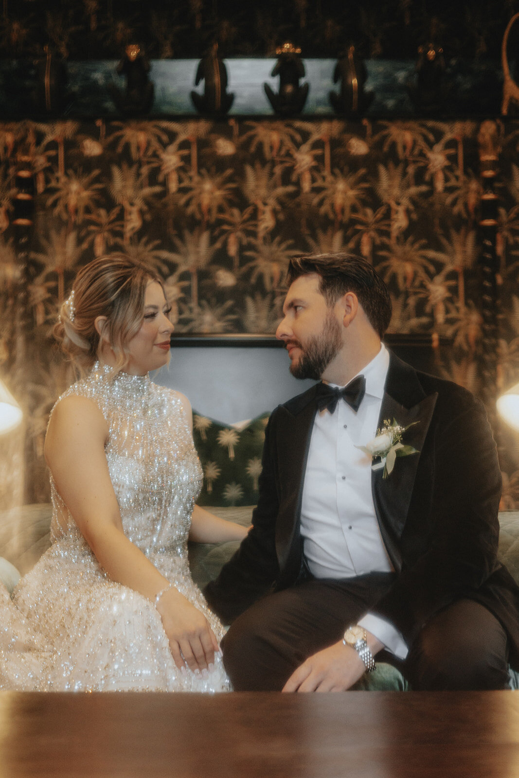 Bride and groom smiling at each other on bed