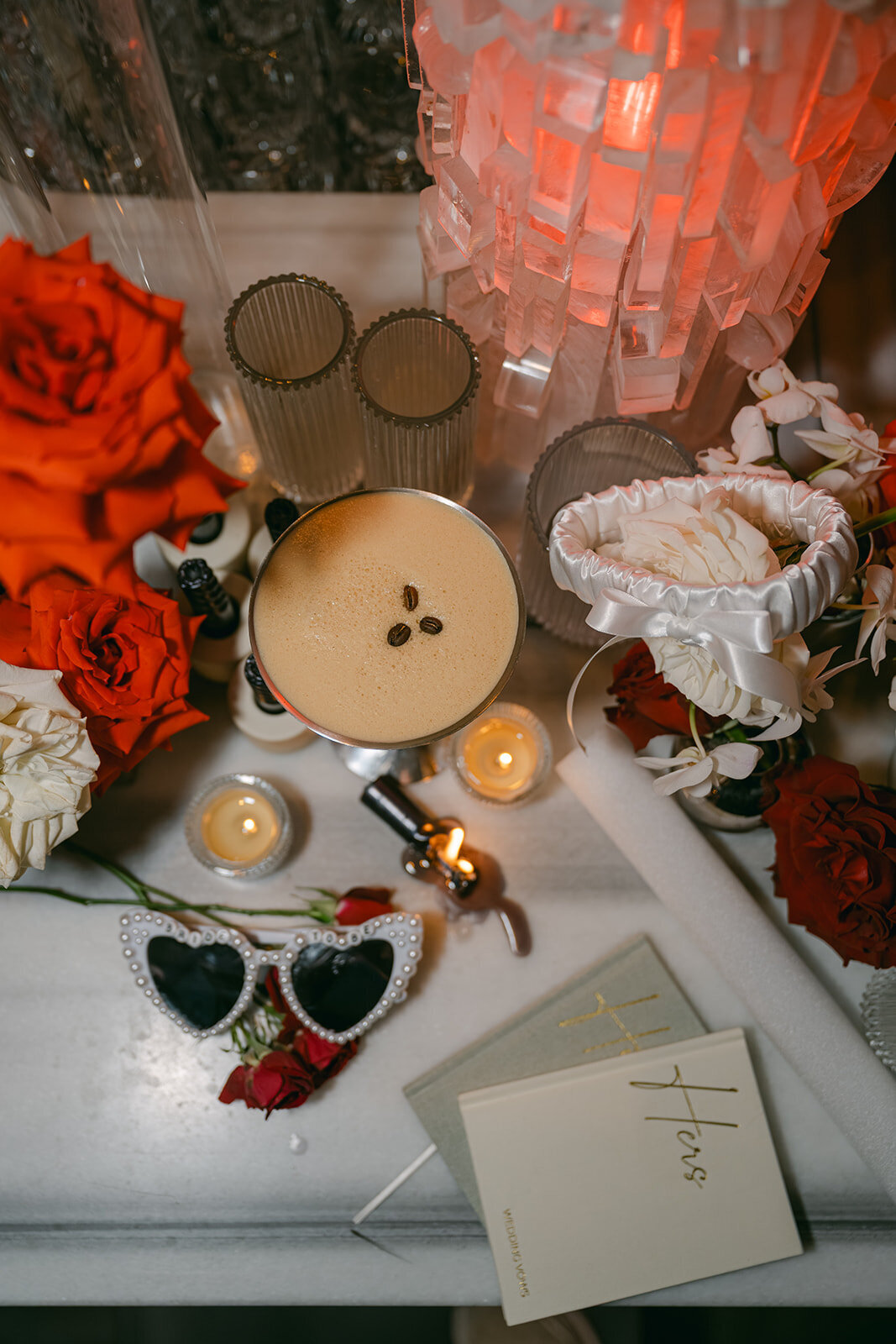 Chic flat lay featuring red and orange florals, high-end bridal earrings, vow books and ring
