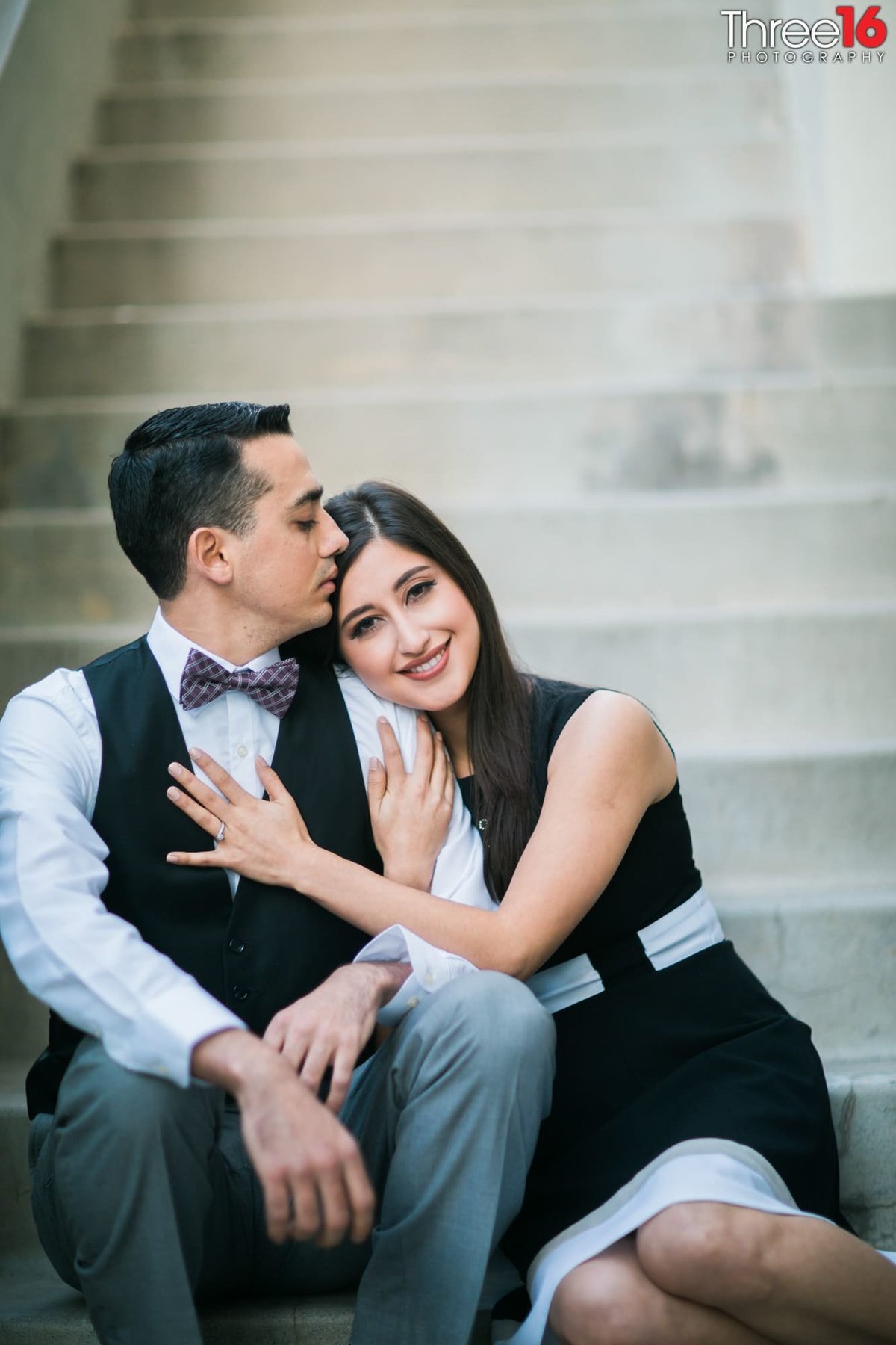 Groom to be kisses his fiance's forehead as she leans up against him