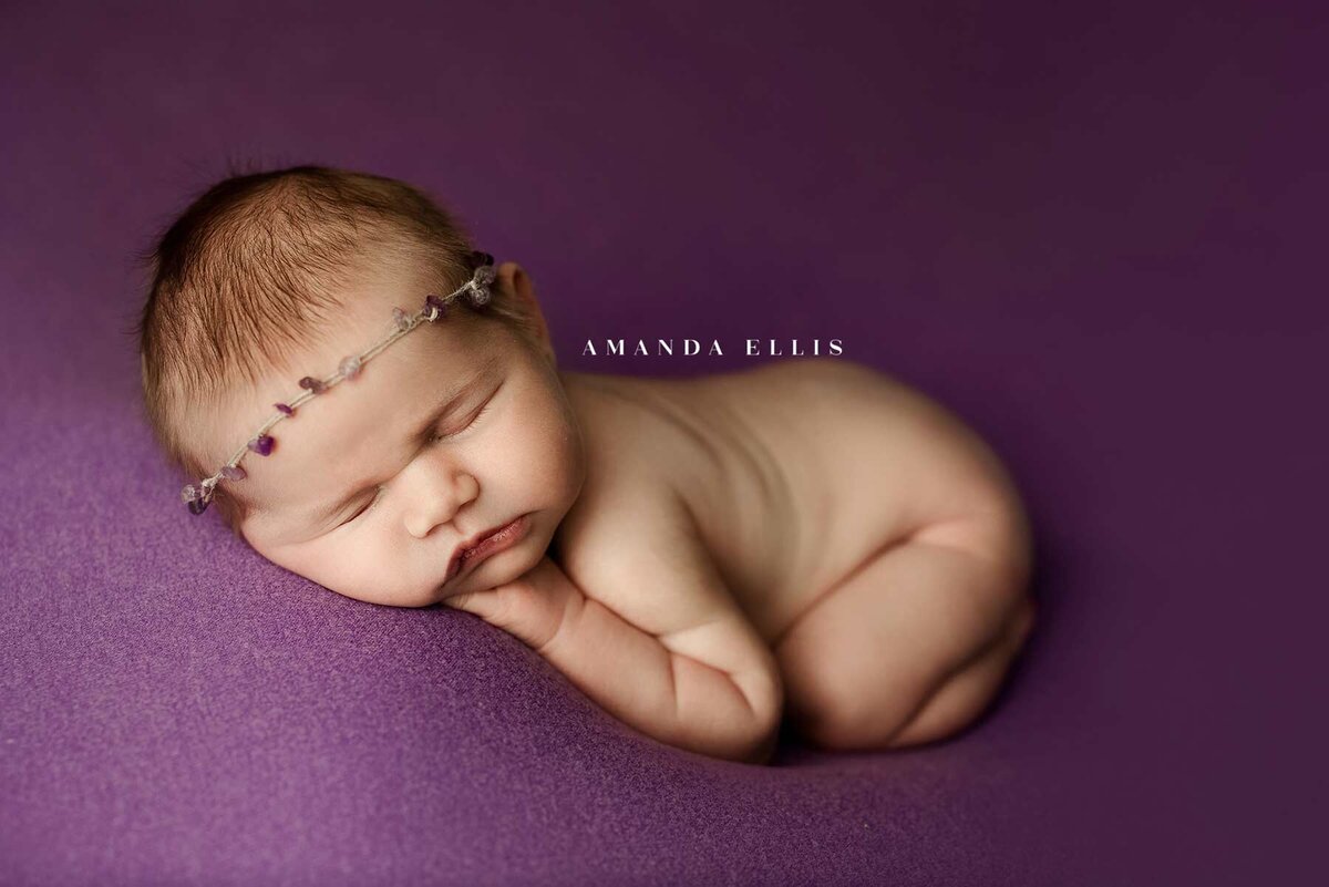 Close up newborn portrait of  baby in purple sheets