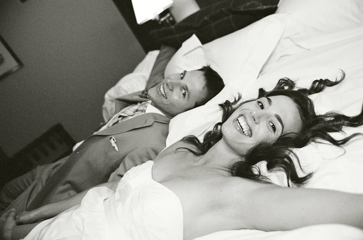bride and groom laying down on bed black and white image