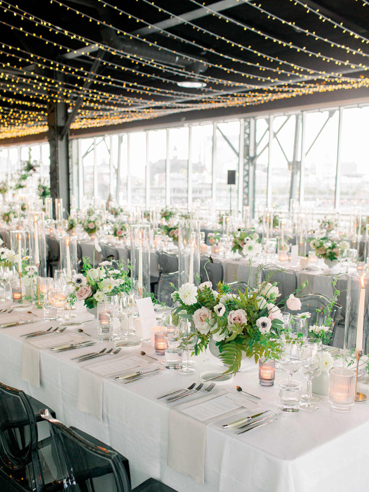 Tables at the Science Centre topped with lush floral arrangements under rows of suspended fairy lights.