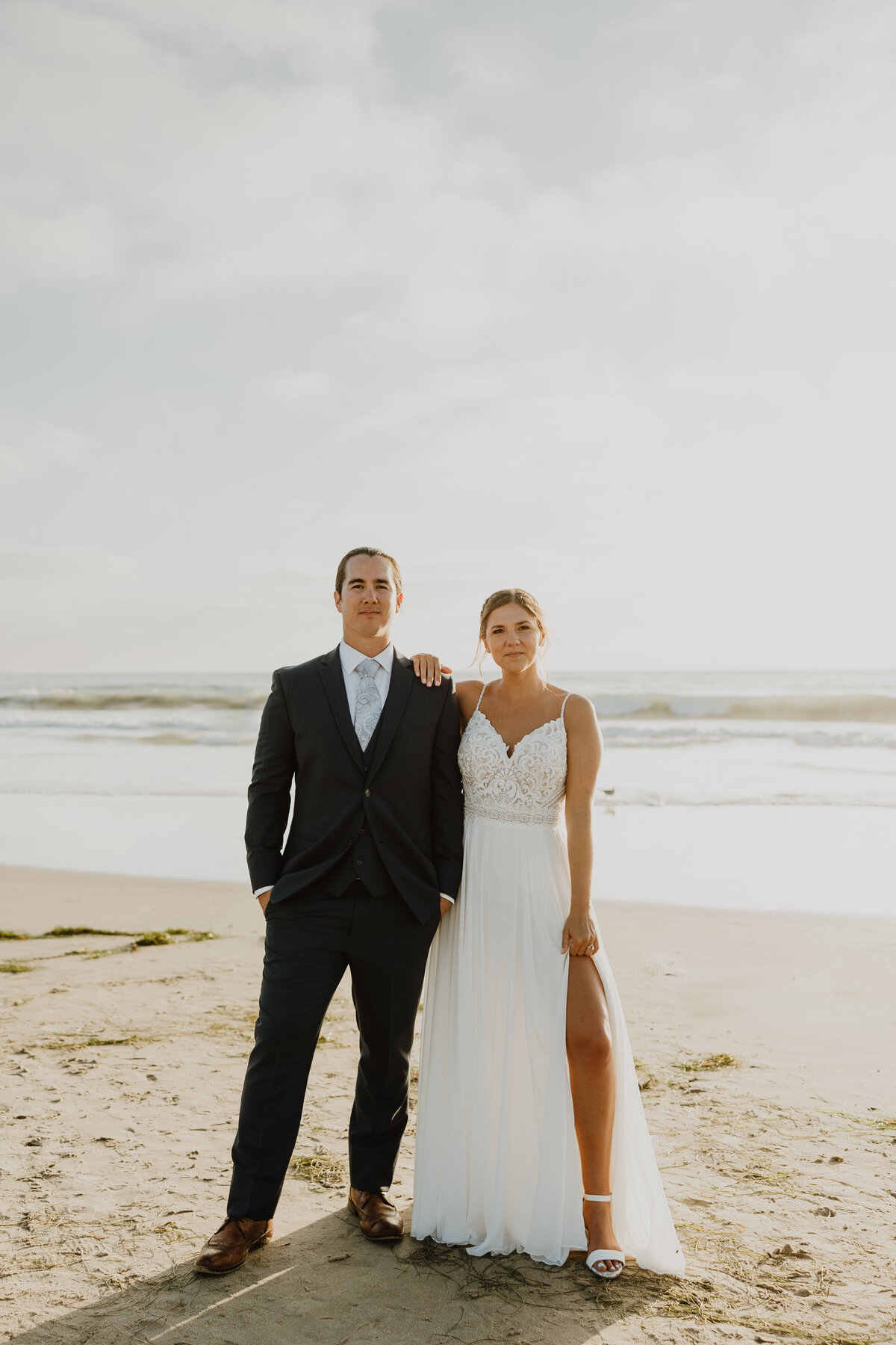 bride and groom looking at camera on beach