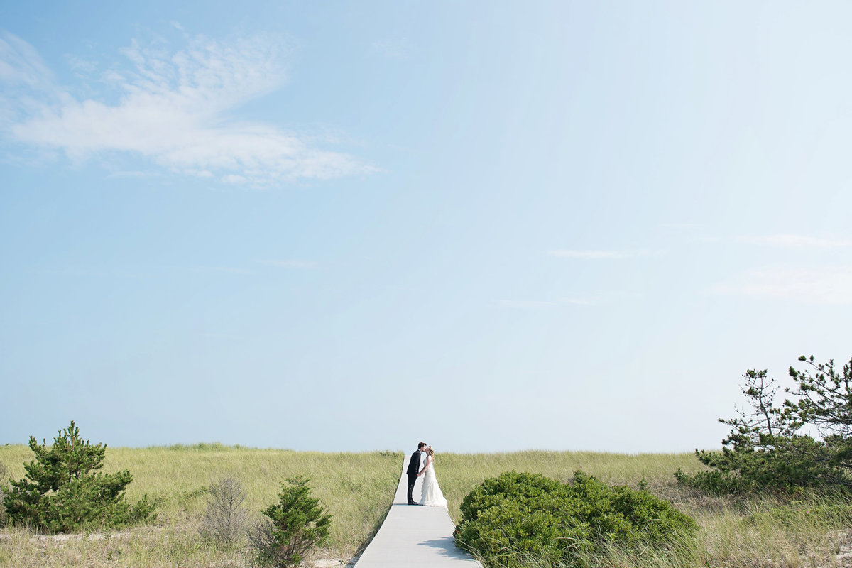 Bride and groom kissing at the boardwalk at Oceanbleu