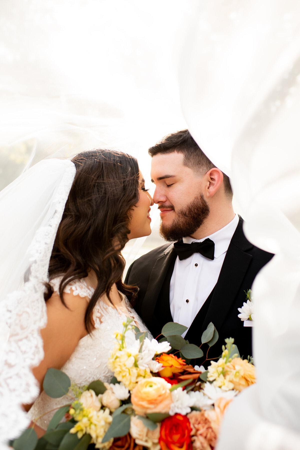 Experience the magic of love with a passionate kiss of the bride and groom, framed by a graceful veil, at Anais Events Center in Bellaire, Texas