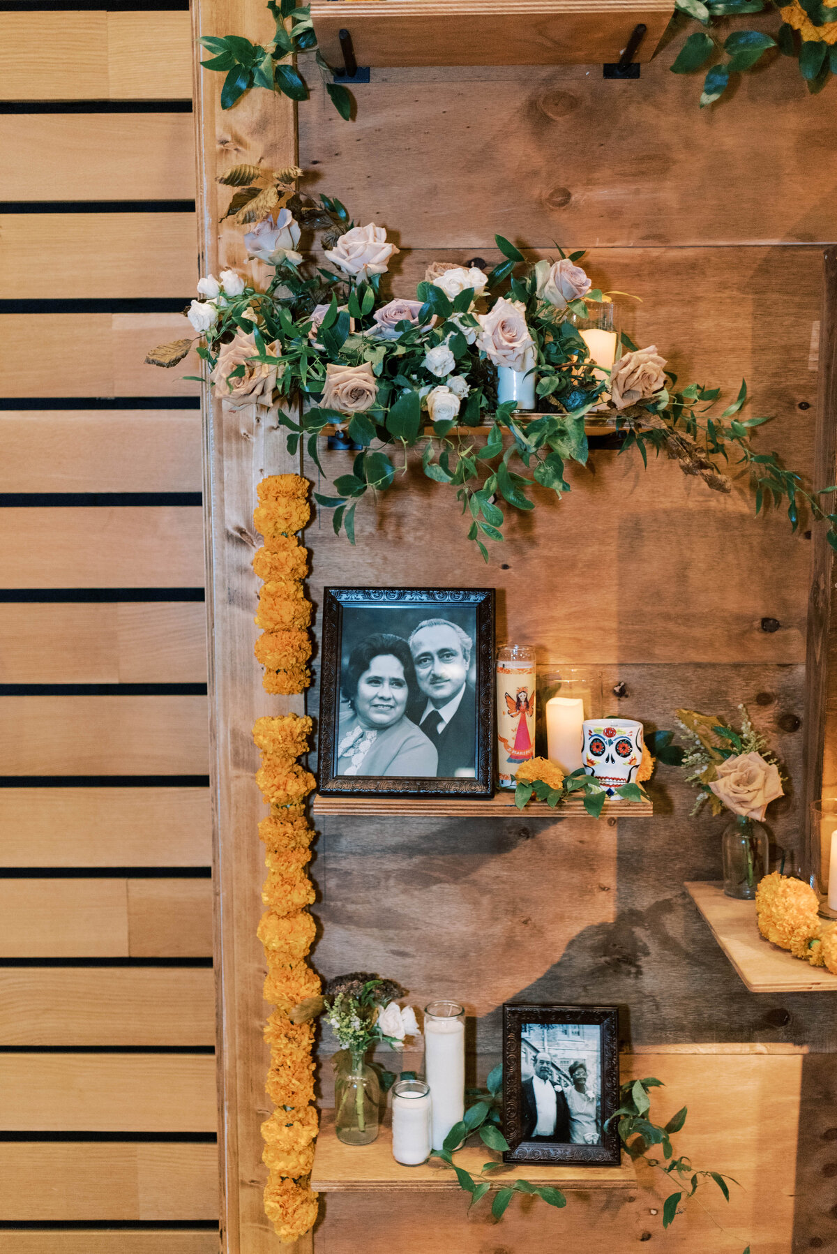 Wedding reception wooden backdrop displaying black and white framed photographs and flowers and greenery