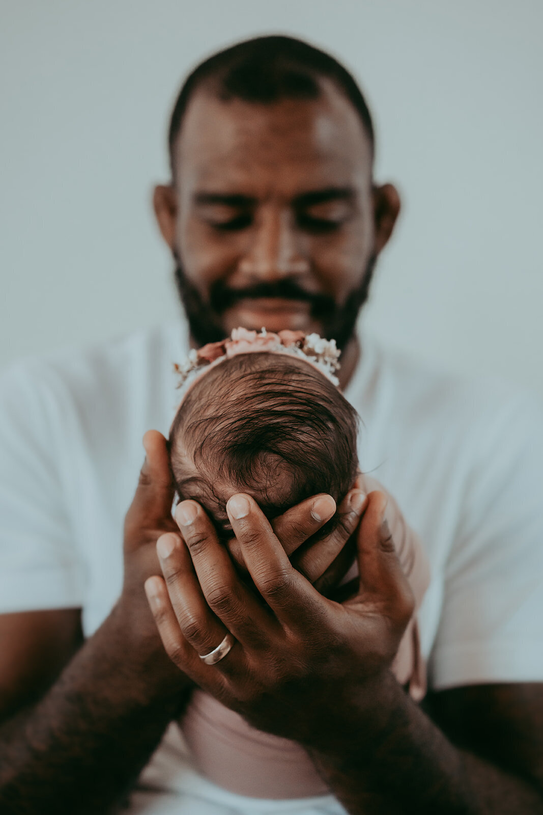 dad's big hands cradle newborn baby's head