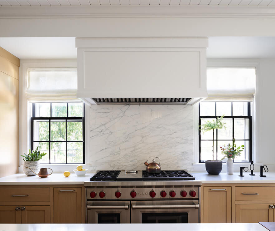 Oak cabinets and a marble backsplash in a historic Hingham home, designed by Boston kitchen and bath designers, blending warmth and elegance with timeless style.
