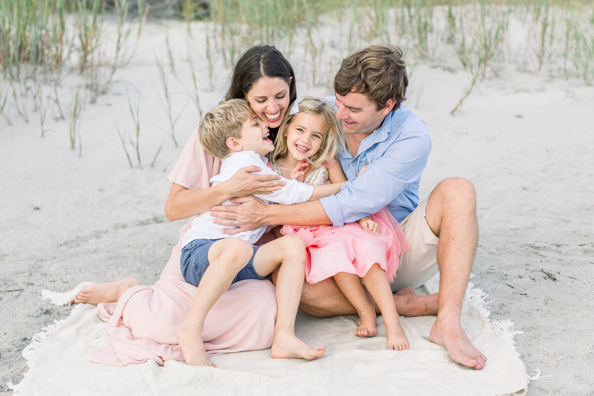 Family embraces seated on Edisto Island beach in South Carolina.