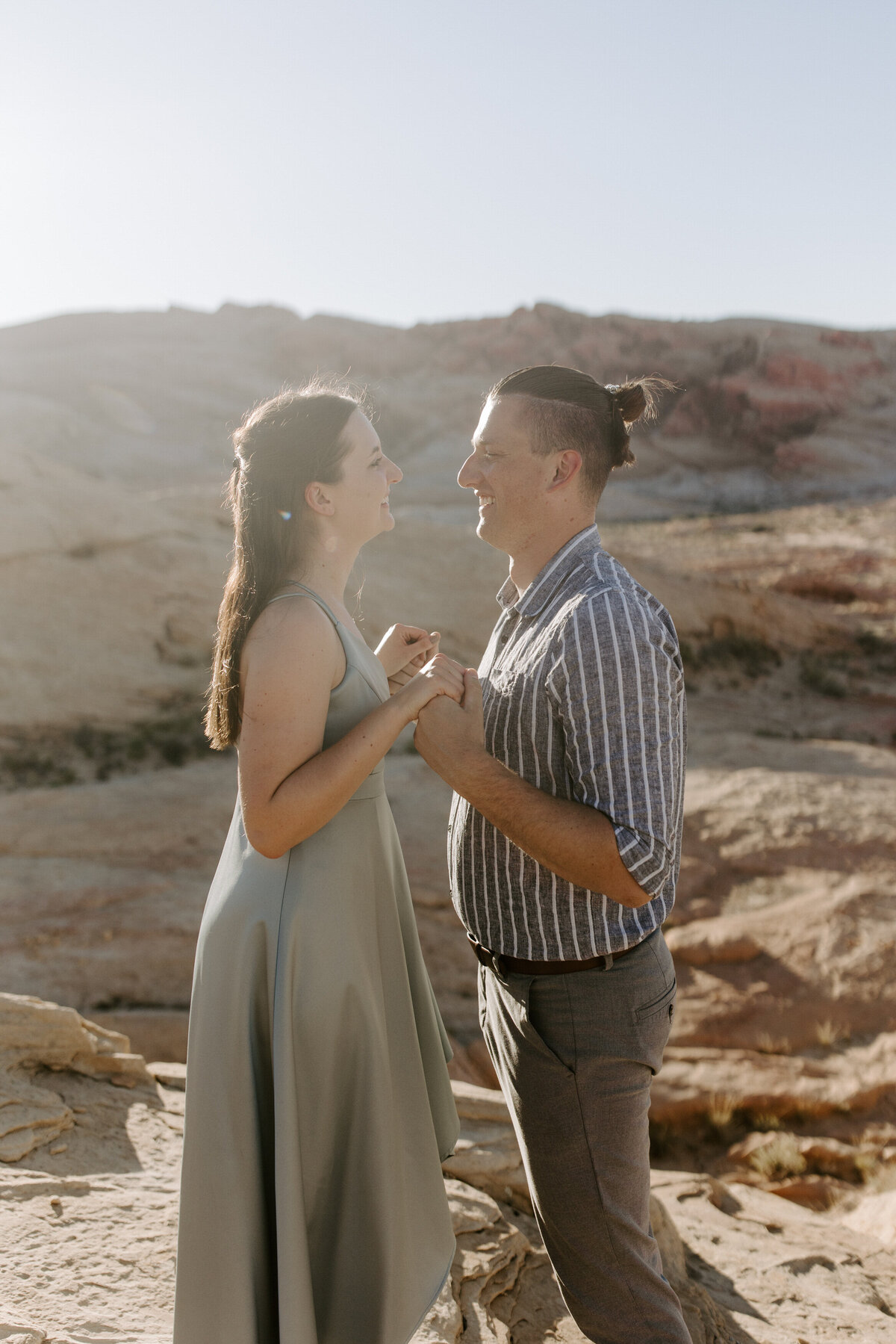 Partners stand face to face holding hands while smiling in Valley of Fire.