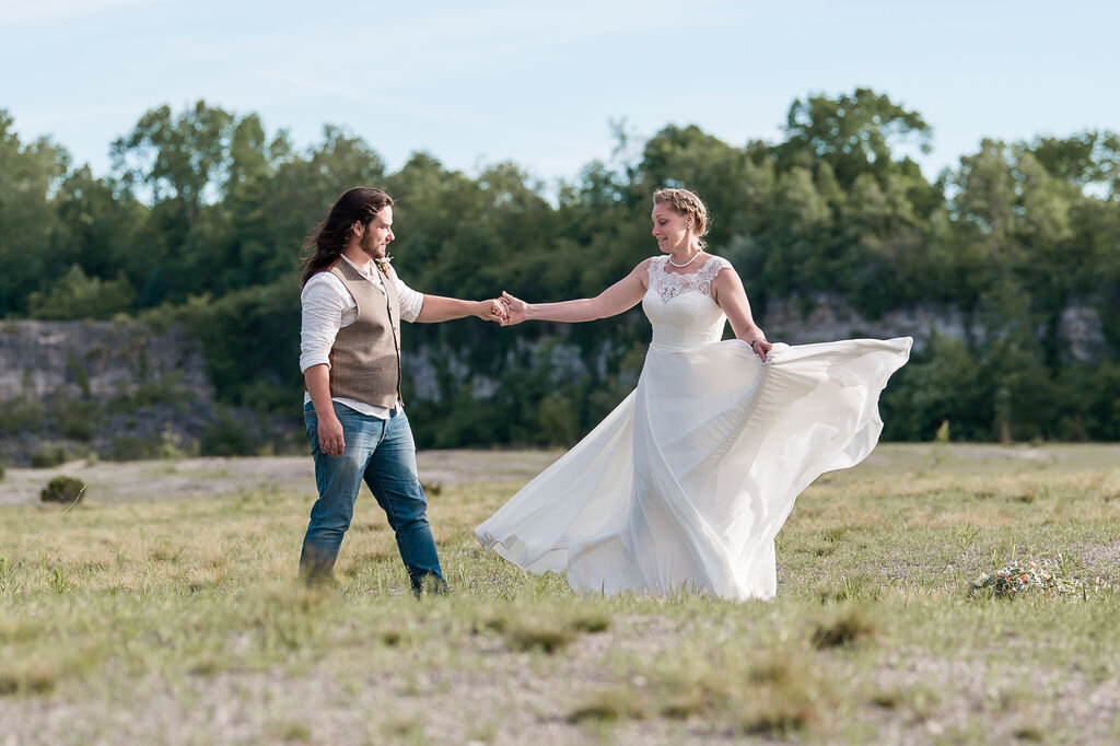 Bride and groom twirl in open field
