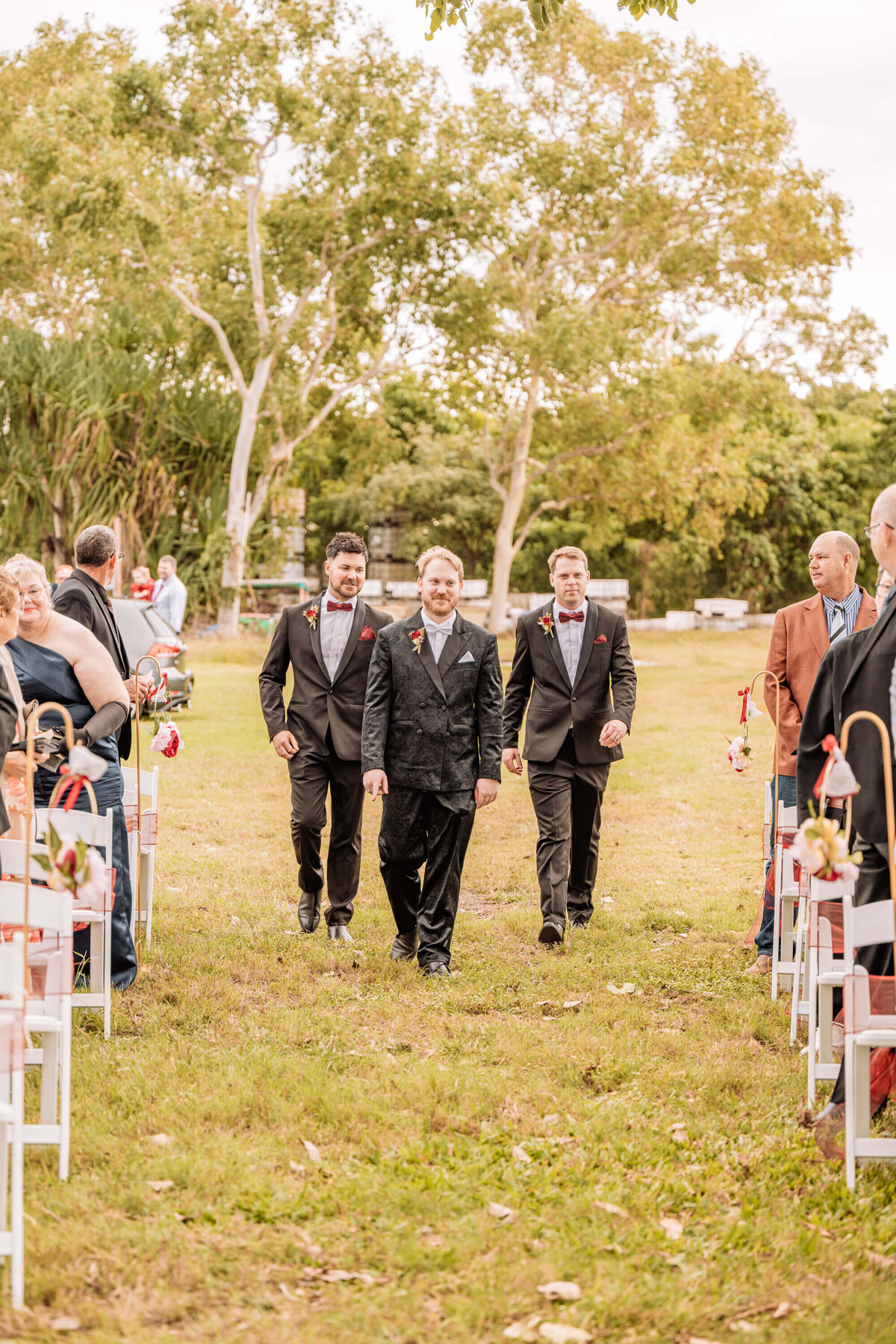 A beautiful outdoor wedding ceremony taking place in a park, surrounded by greenery and floral decorations. - photo by Jamie Simmons