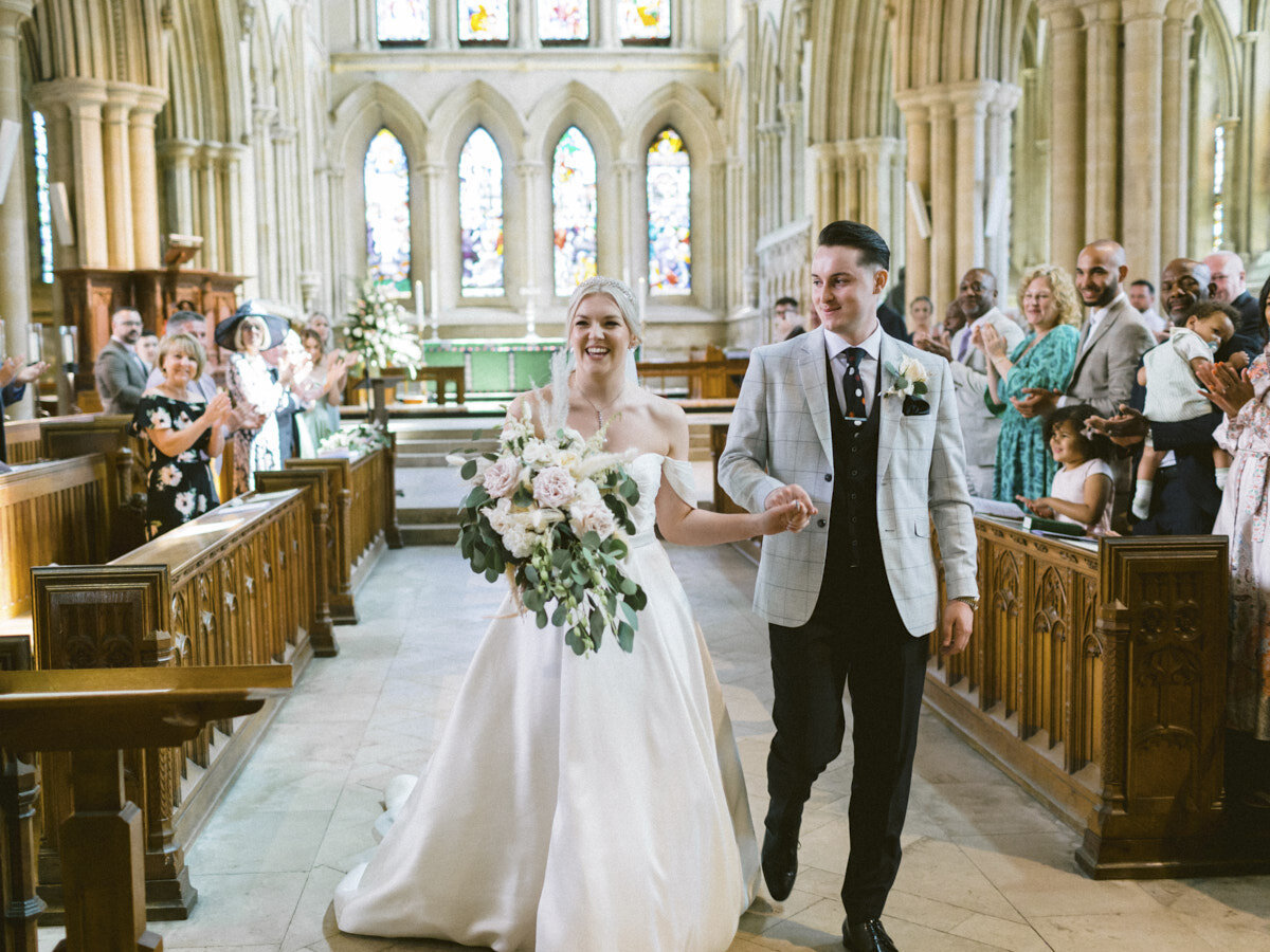 lincolnshire wedding bride and groom handing hands and smiling exiting the church after wedding ceremony 