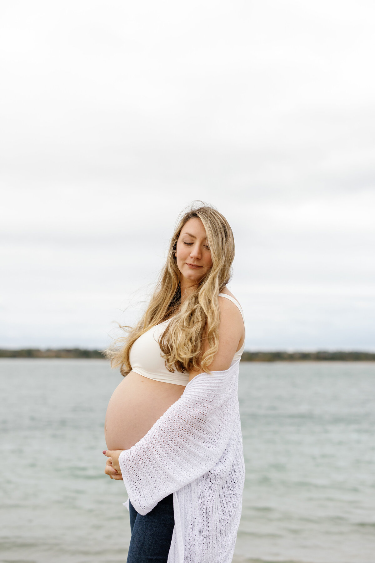 Pregnant woman in flowing dress walking along Wilmington beach, coastal maternity photography