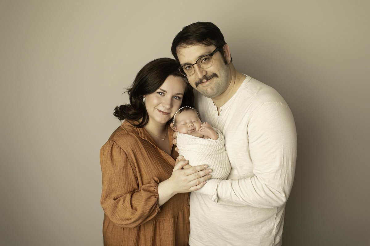 First-time mom and dad lovingly snuggle their newborn baby, sharing a tender and intimate moment filled with warmth and joy