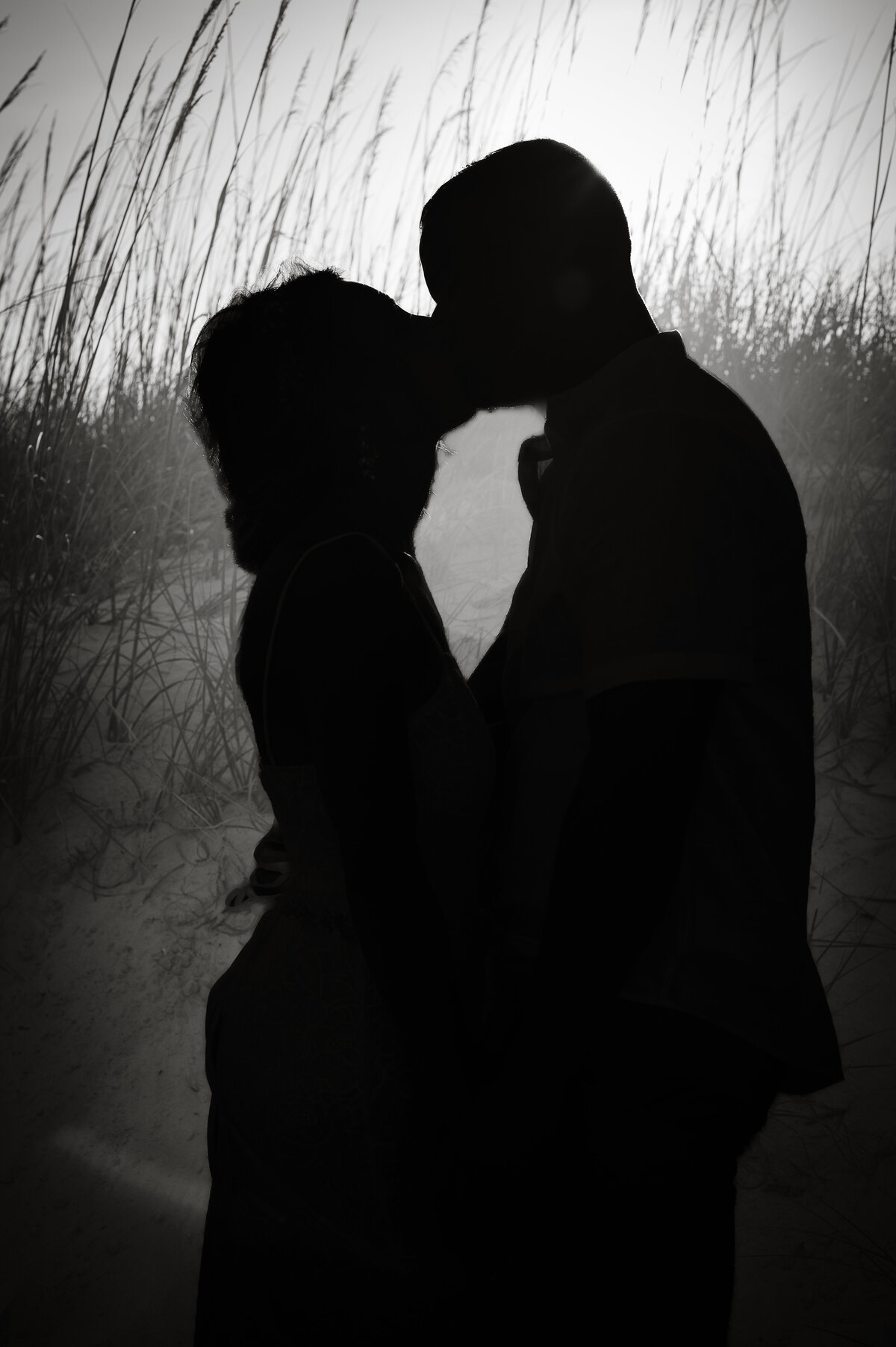 Silhouette of bride and groom kissing on beach 