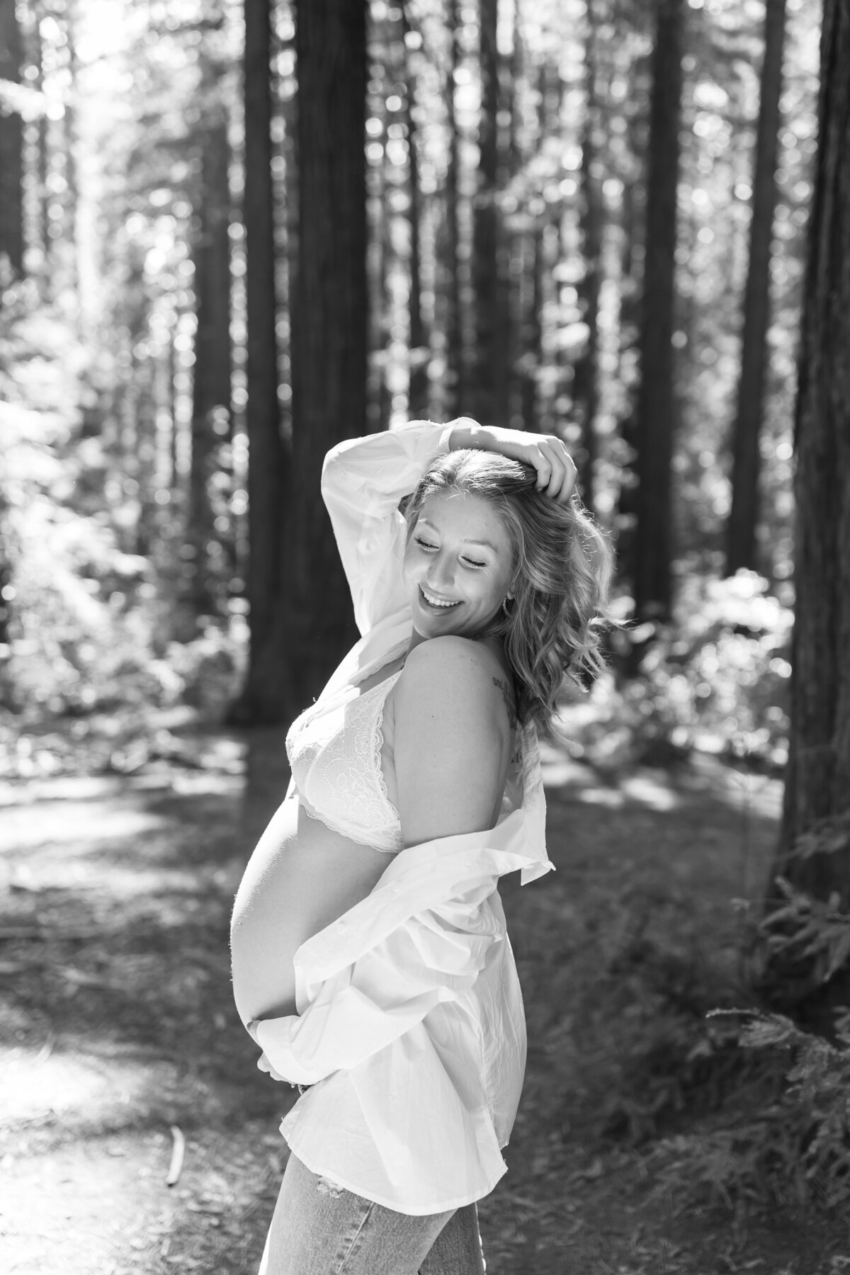 pregnant woman holding her belly smiling in a forest