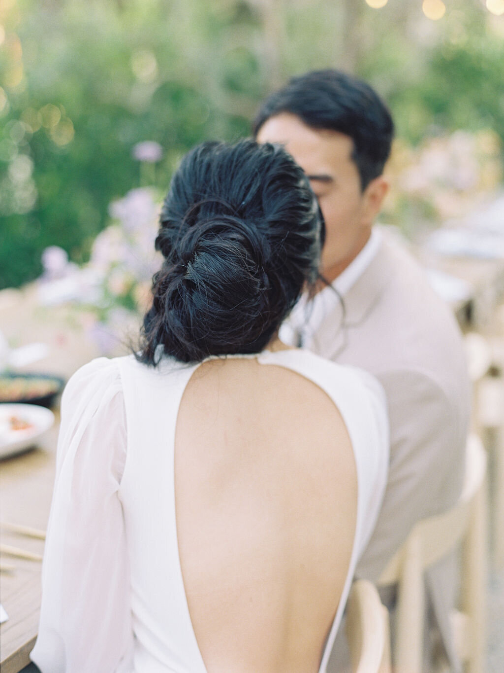 back of bride kissing groom