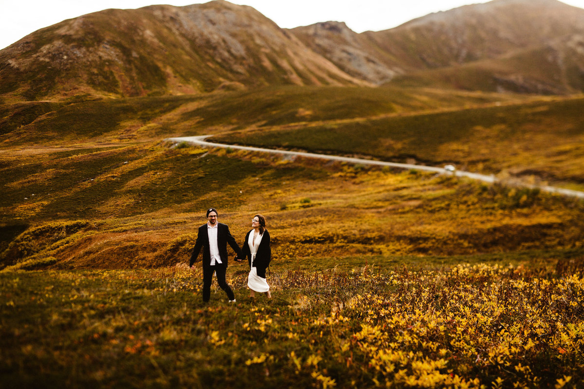 elopement couple walks through fall colored mountaintop tundra  at hatcher pass