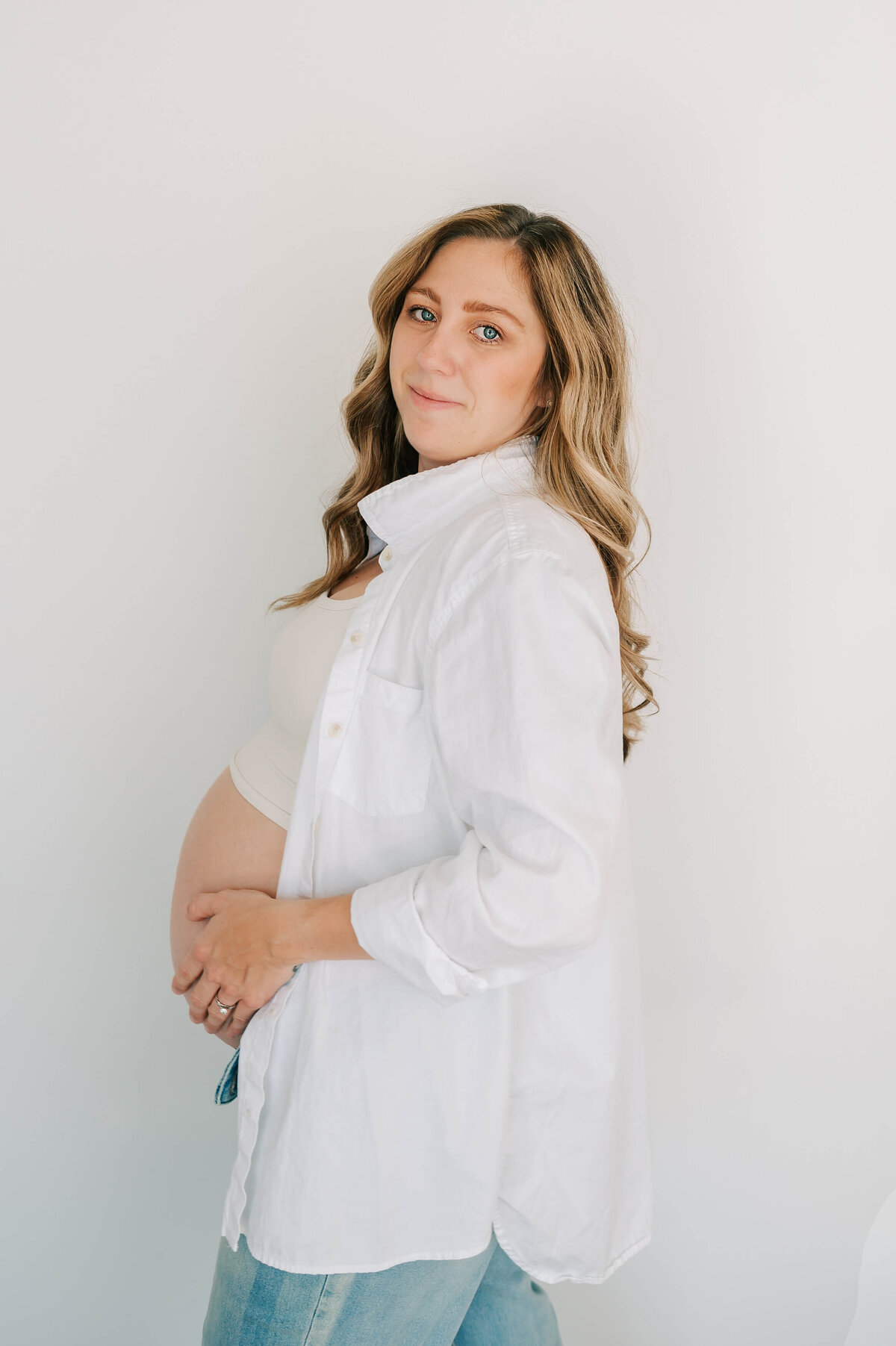 pregnant mom in jeans holding bump during Branson MO maternity photography session