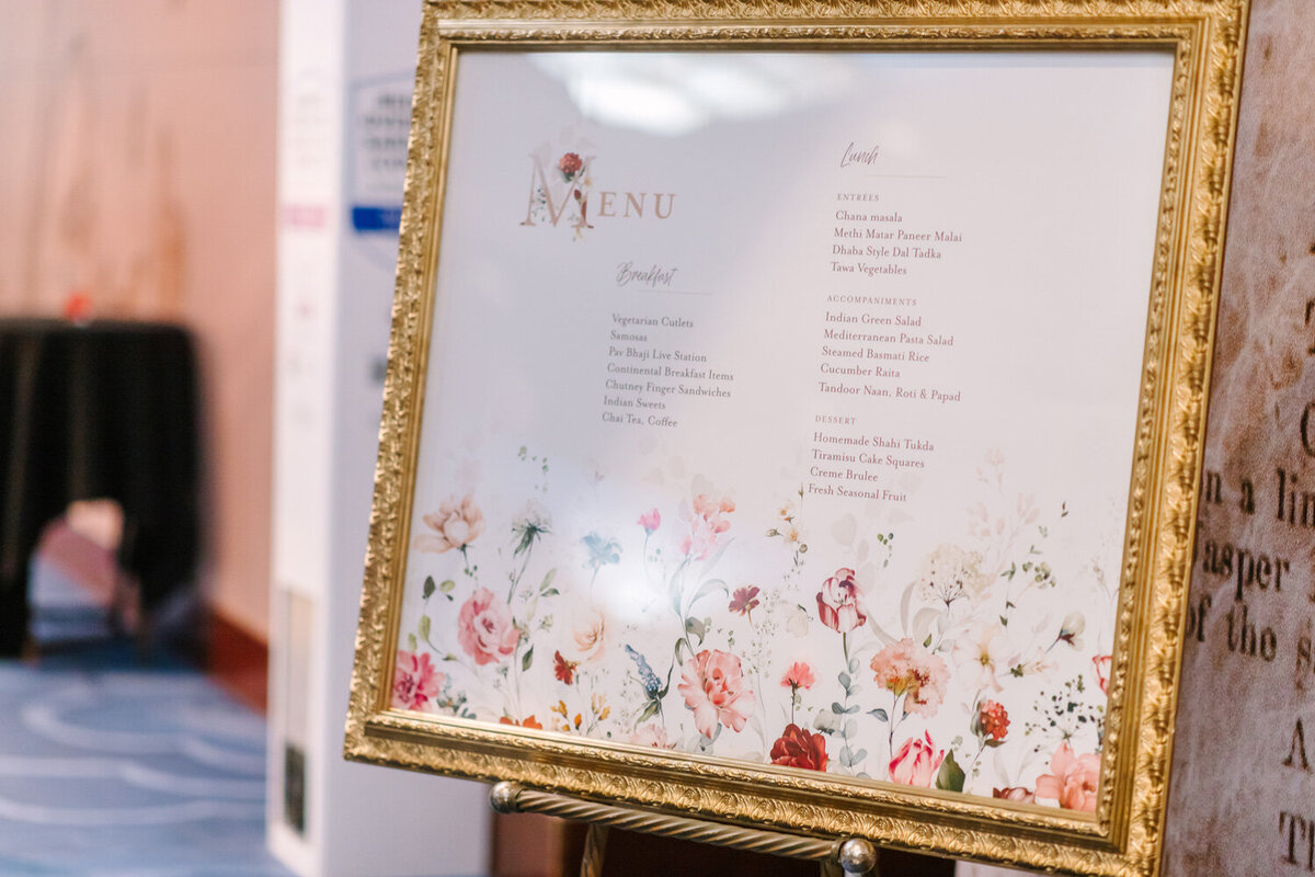 Seating chart at the wedding in a gold frame with pink flowers.