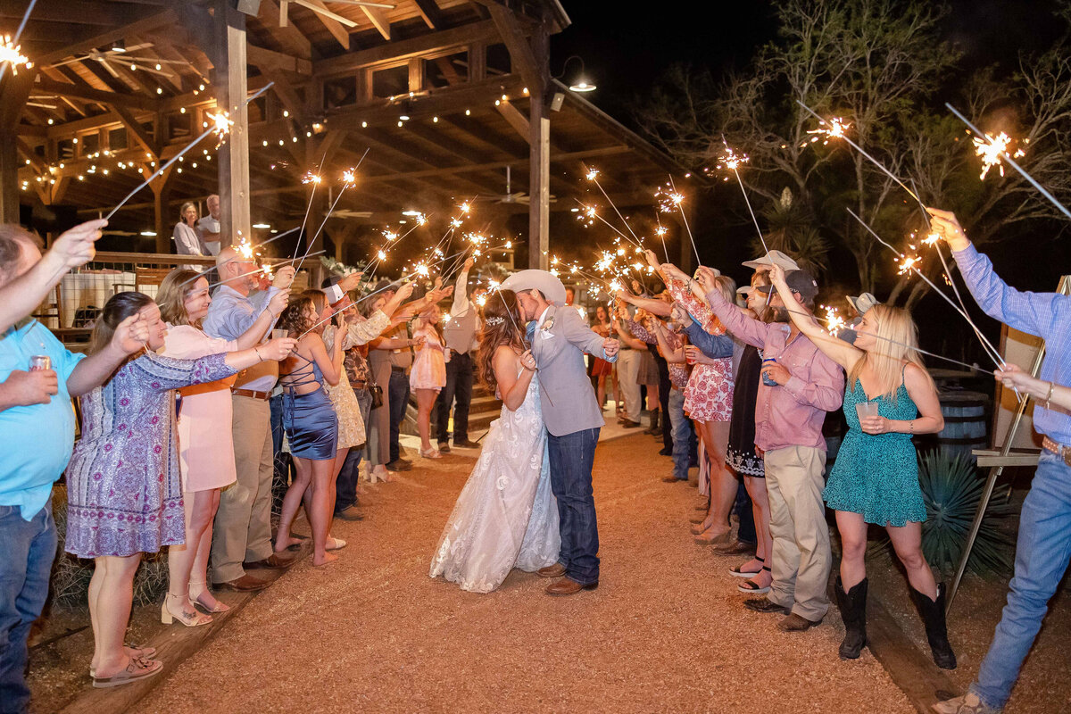bride and groom kiss at Texas wedding sparkler exit in cowboy hat San Antonio
