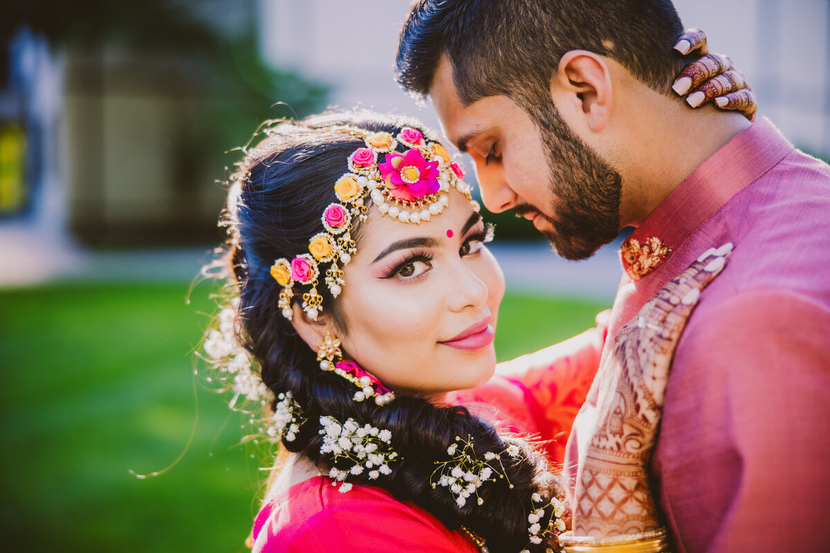 A pakistani groom and bengali bride share a moment during the holud mehndi day as the bride wears a floral headpiece