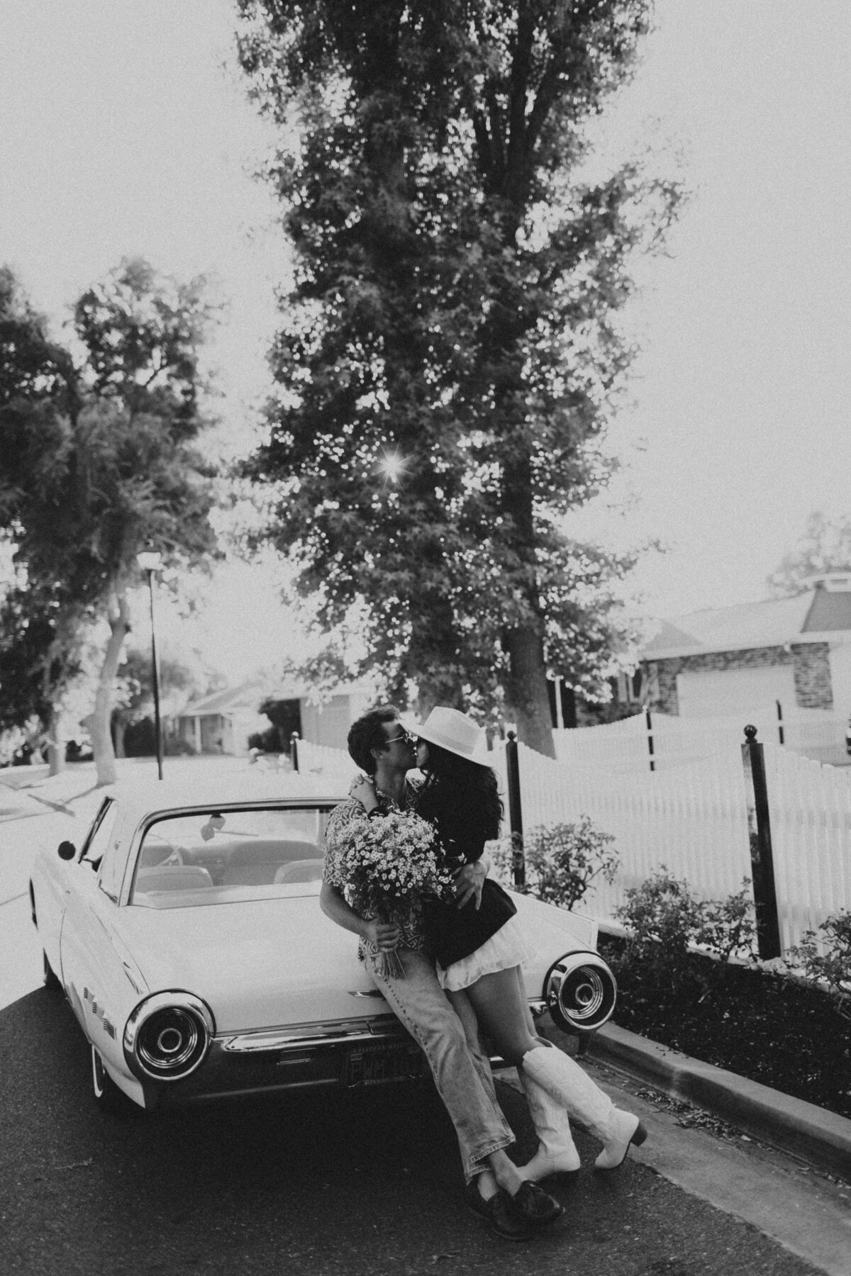 couple leaning against classic car kissing