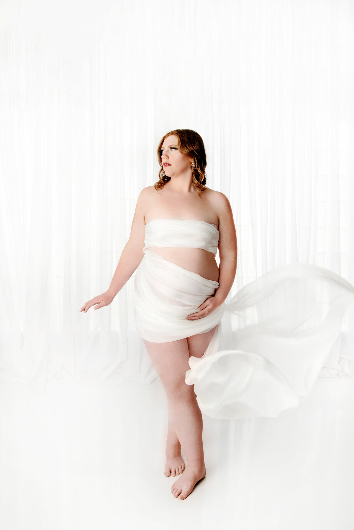 st-louis-maternity-photographer-pregnant-woman-wrapped-in-white-fabric-on-white-backdrop