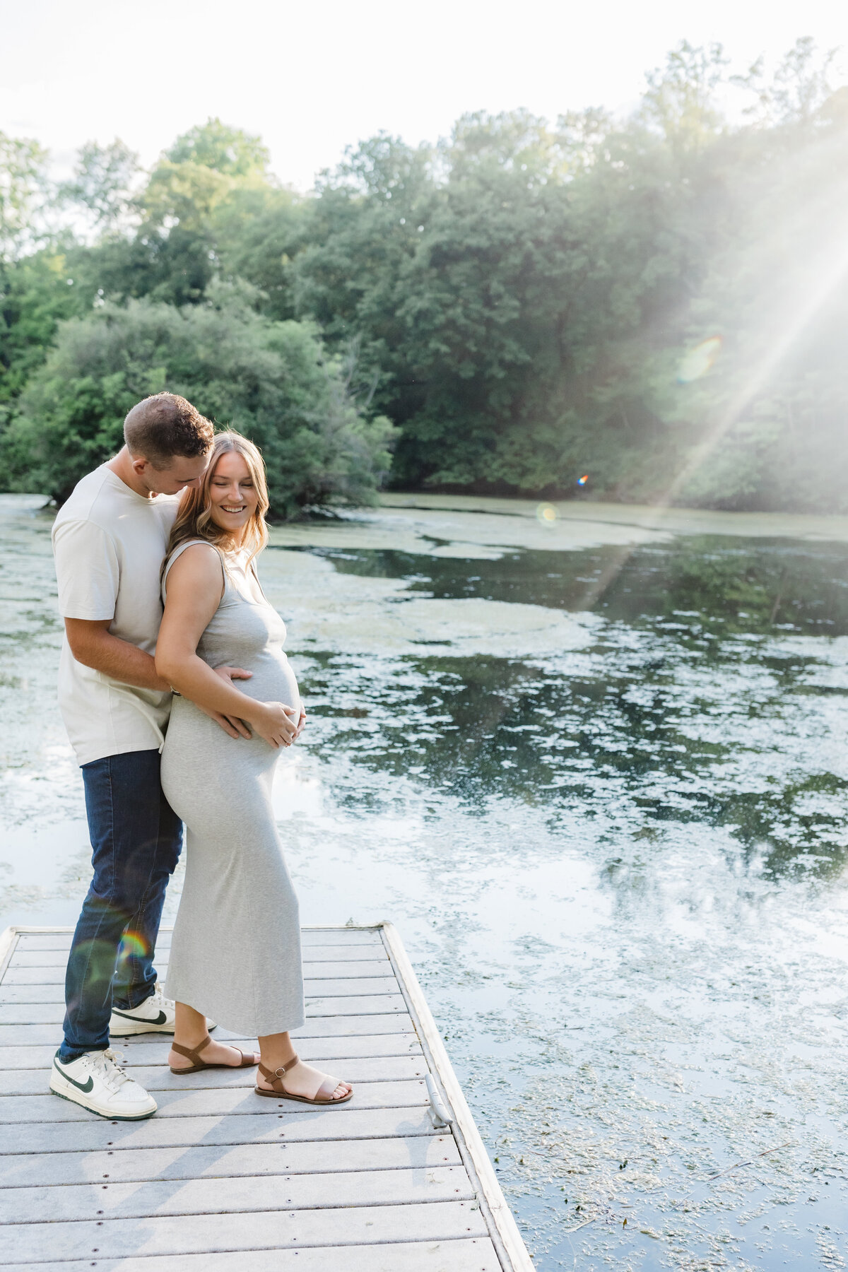 Couple standing on a dock, holding hands and looking at each other near a serene lake in South Bend.