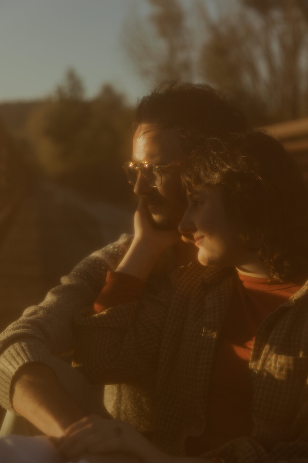 Intimate photo of engagement couple where guy is holding girl as they look at the sunset 