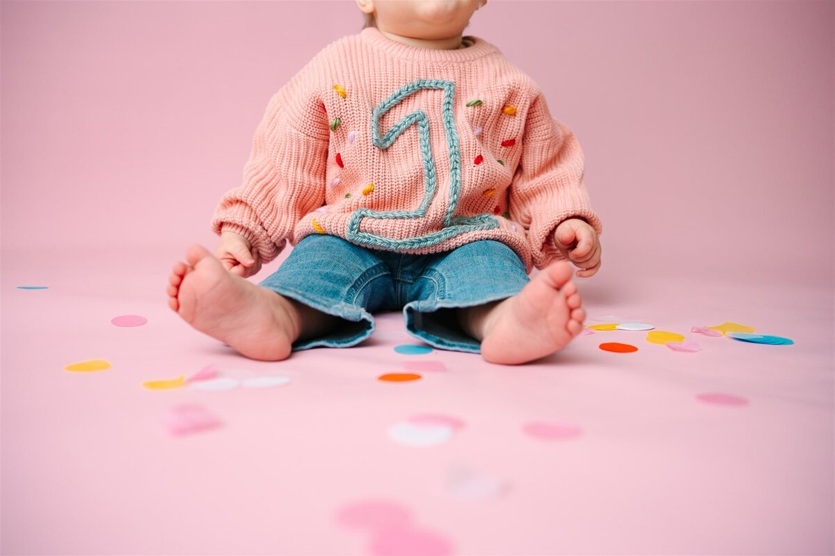 a small child sitting on the ground with confetti around them